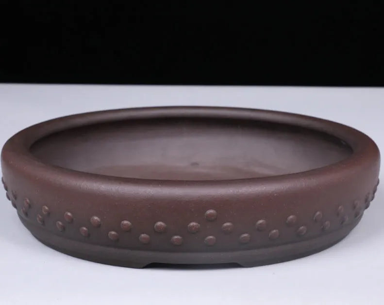 Classical handmade purple clay ceramic flowerpot with large round mouth on a wooden table