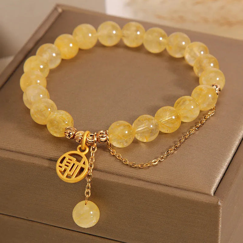 Women's natural citrine bracelet with gold electroplated Chinese character charm on an adjustable dark cord.