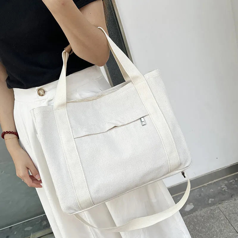 Canvas crossbody tote bag in khaki with open zipper showing internal organiser pockets.