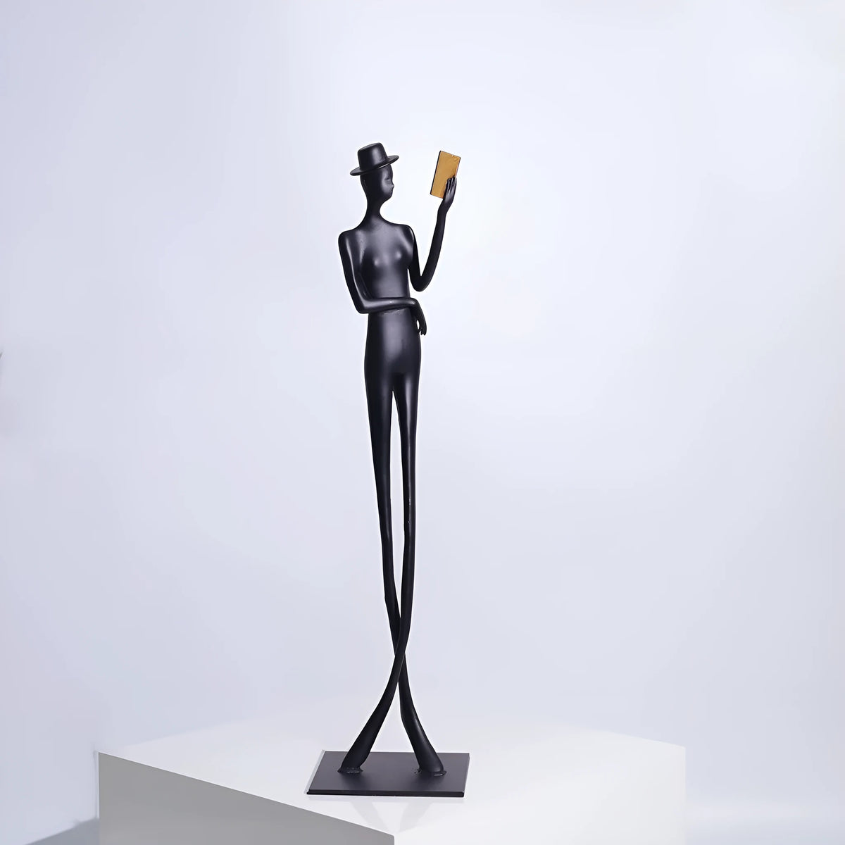 Black metal cast aluminium reading woman sculpture on desk, modern minimalist style