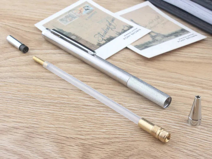 Silver metal automatic mechanical pencil with six compatible lead sizes from 0.5mm to 2.0mm on a notebook.