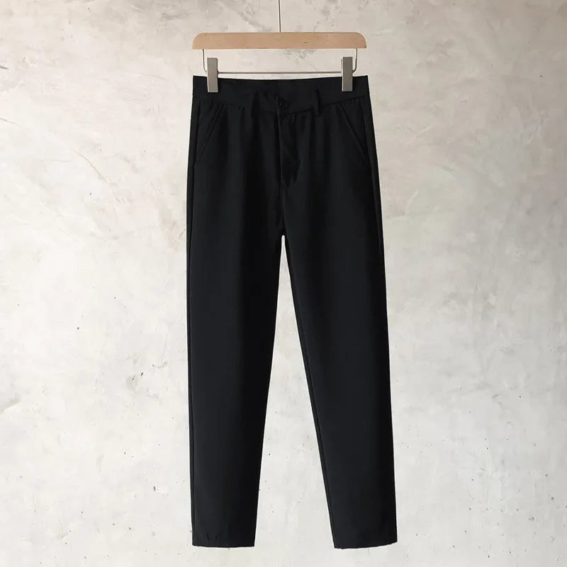 Boy wearing slim straight tapered wool trousers in a grey colour, showing the straight leg opening and belt loops.