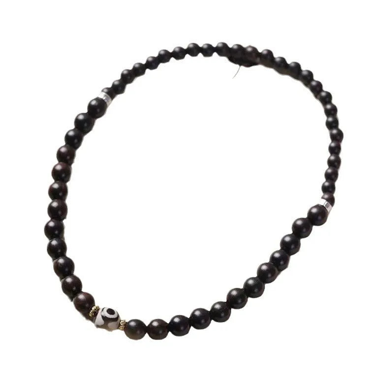 Close-up of a dark ebony wood bracelet with two smooth bead circles on a wrist.
