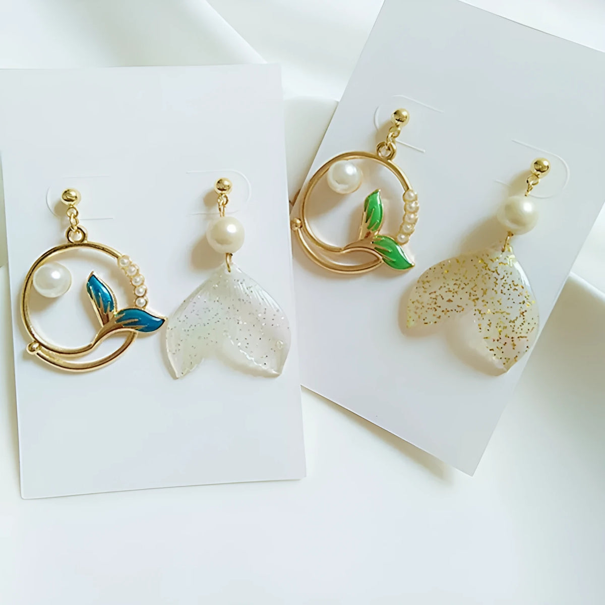 Asymmetric fishtail earrings in electroplated alloy with pearl and geometric design, green and blue options