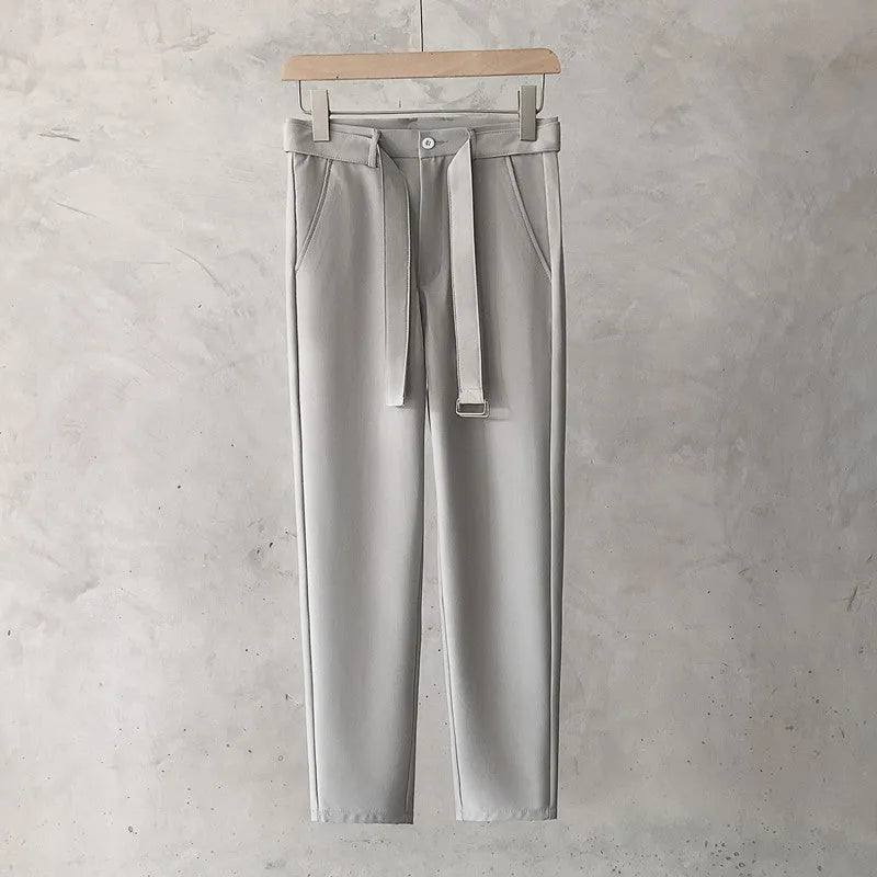 Boy wearing slim straight tapered wool trousers in a grey colour, showing the straight leg opening and belt loops.