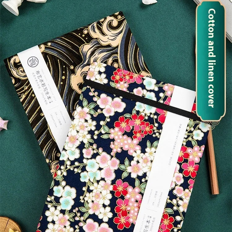 Feiluniao handmade fabric watercolour notebook open on a table with paintbrush.