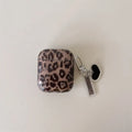 Transparent brown leopard printed PC earphone sleeve on Apple AirPods charging case showing visible logo and spotted pattern