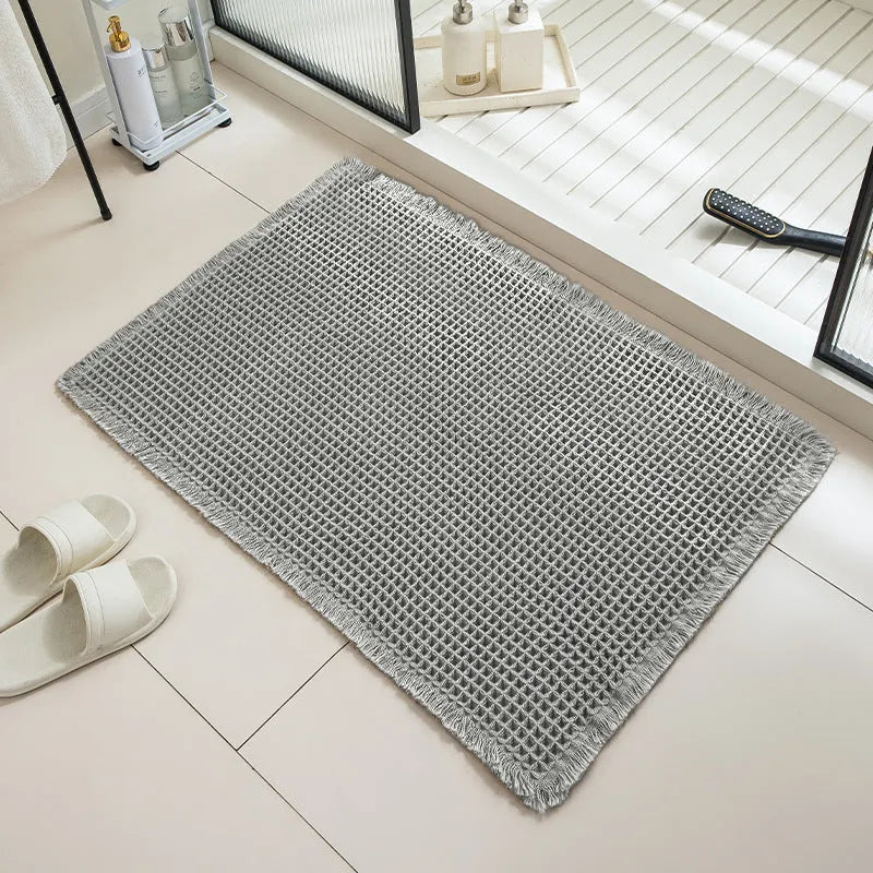 Beige and white checkered woven polyester bathroom floor mat on tiles.