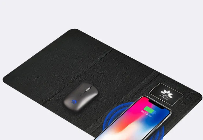 Folding cloth wireless charging mouse pad next to a small white wireless mouse on a desk