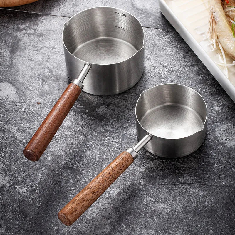 Two 304 stainless steel dog food scoops with wooden handles on a surface