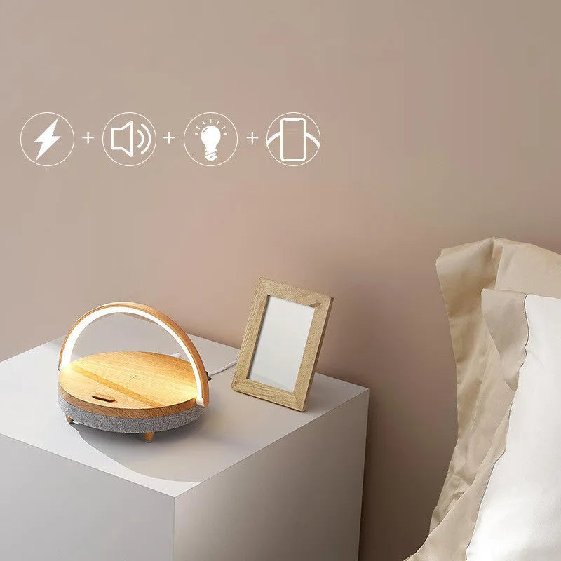 Marble pattern wireless charging LED night light with Bluetooth speaker and phone holder on a wooden nightstand.