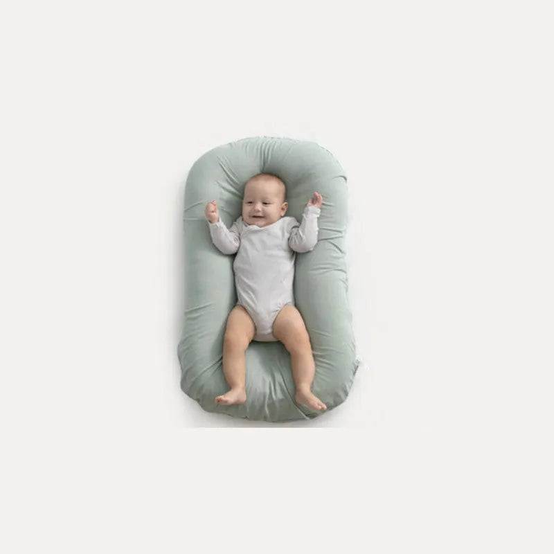 Beige portable cotton baby nest crib for newborns on a neutral background