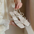 Women's flat beige Roman sandals with multiple straps and a square open toe.