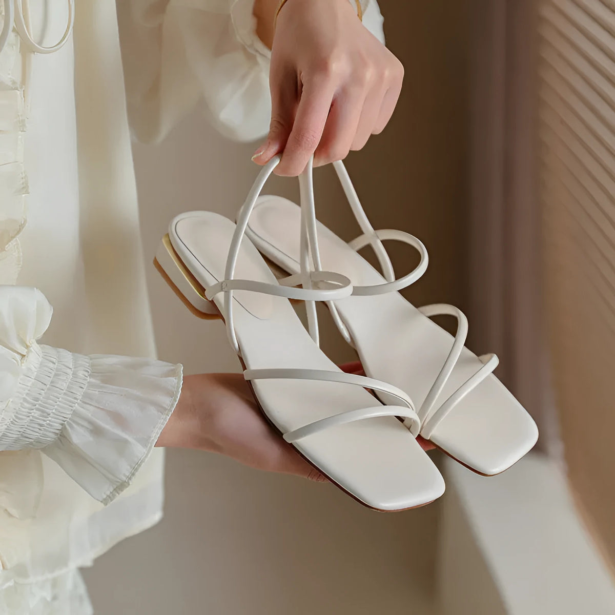 Women's flat beige Roman sandals with multiple straps and a square open toe.