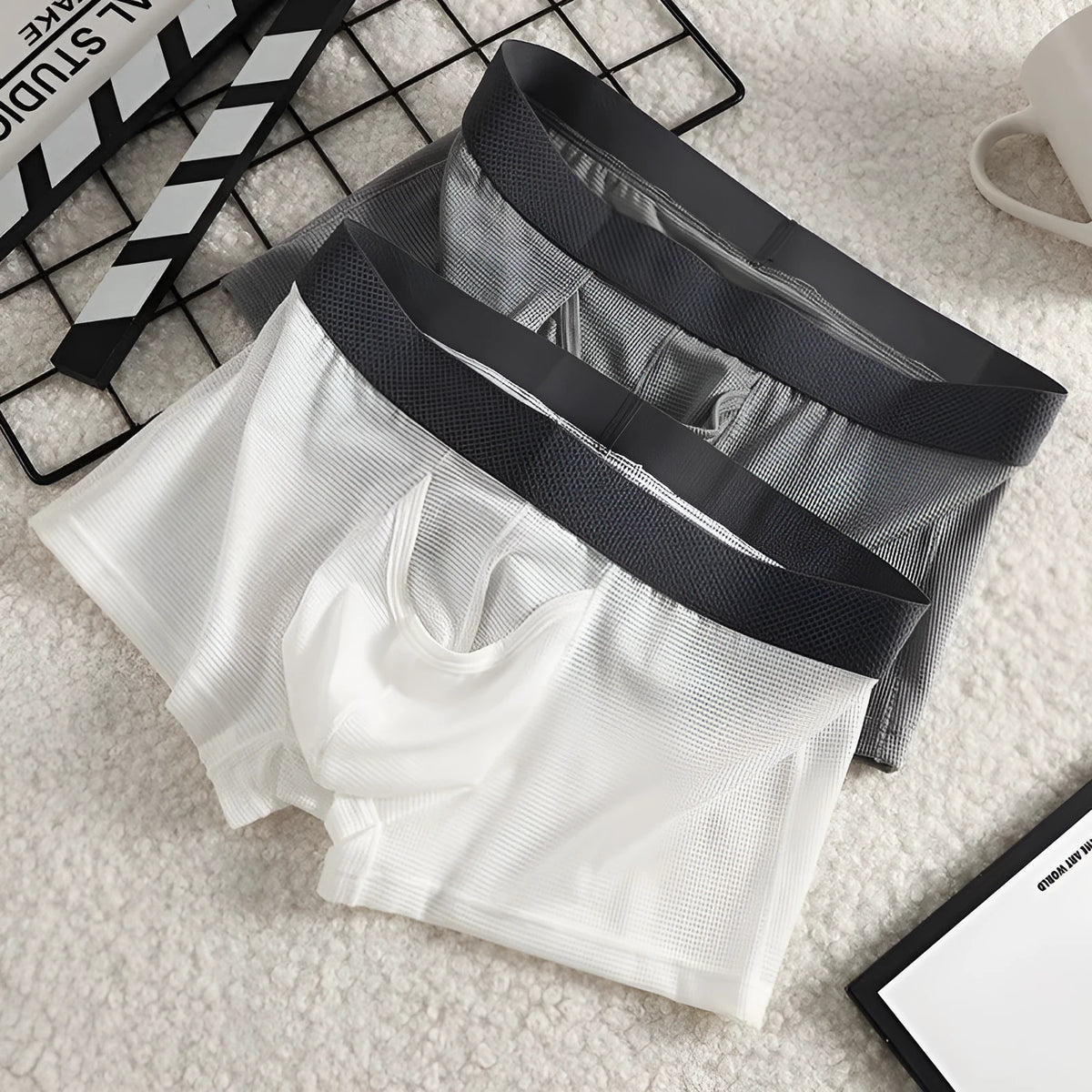 Men's black Ice Silk mesh boxer shorts laid flat, showing low-rise waistband and breathable fabric texture.