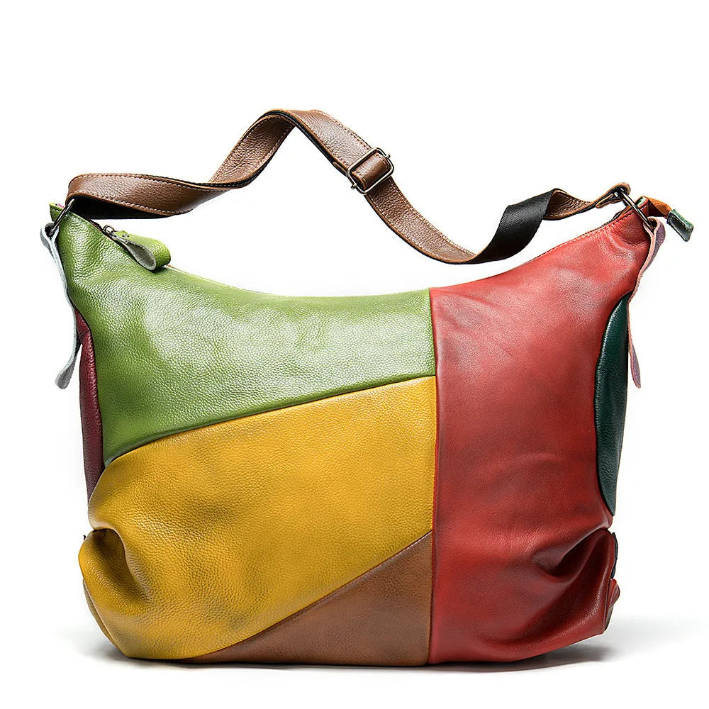 Brown cowhide leather crossbody travel bag with stitching, holding a laptop and magazine.