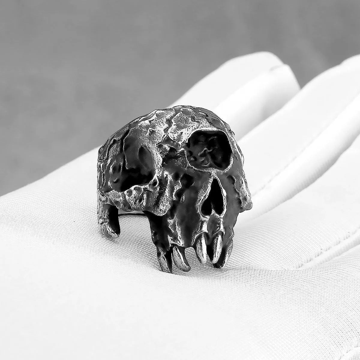 Silver tone alloy ring featuring a detailed one-eyed skull design on a black background.