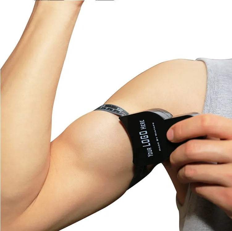 Black ABS plastic body fat caliper with measurement scale and included flexible measuring tape.