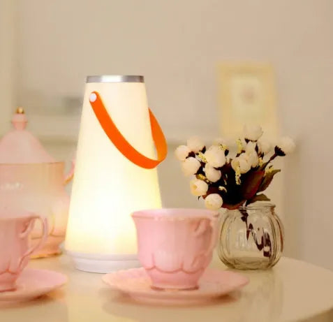 White rechargeable LED bedside night light with touch control on a wooden table.