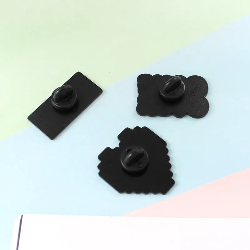 A three-dimensional die-cast alloy metal badge shaped like a stereo game console.