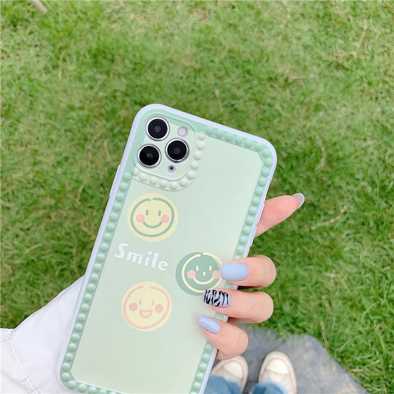 Green TPU iPhone case with a smiley face geometric pattern and polka dot frame.