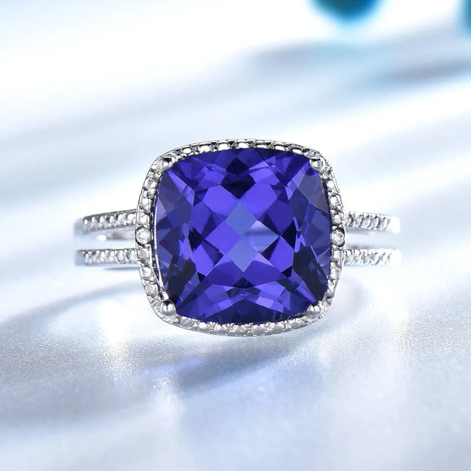 Blue tanzanite gemstone set in a silver women's ring on a finger.