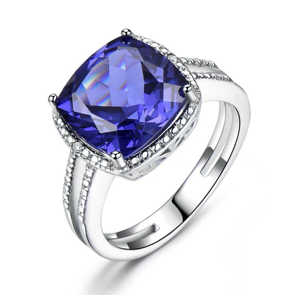 Blue tanzanite gemstone set in a silver women's ring on a finger.