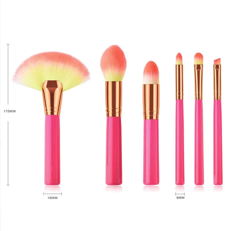 Pink cosmetic makeup brush set with wooden handles and synthetic nylon bristles on a flat surface