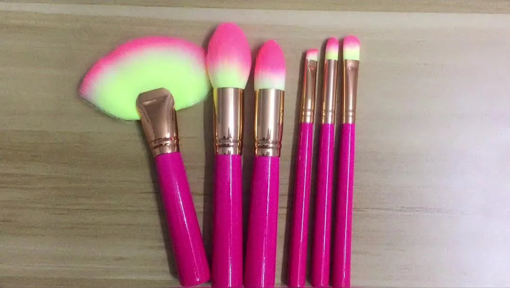 Pink cosmetic makeup brush set with wooden handles and synthetic nylon bristles on a flat surface