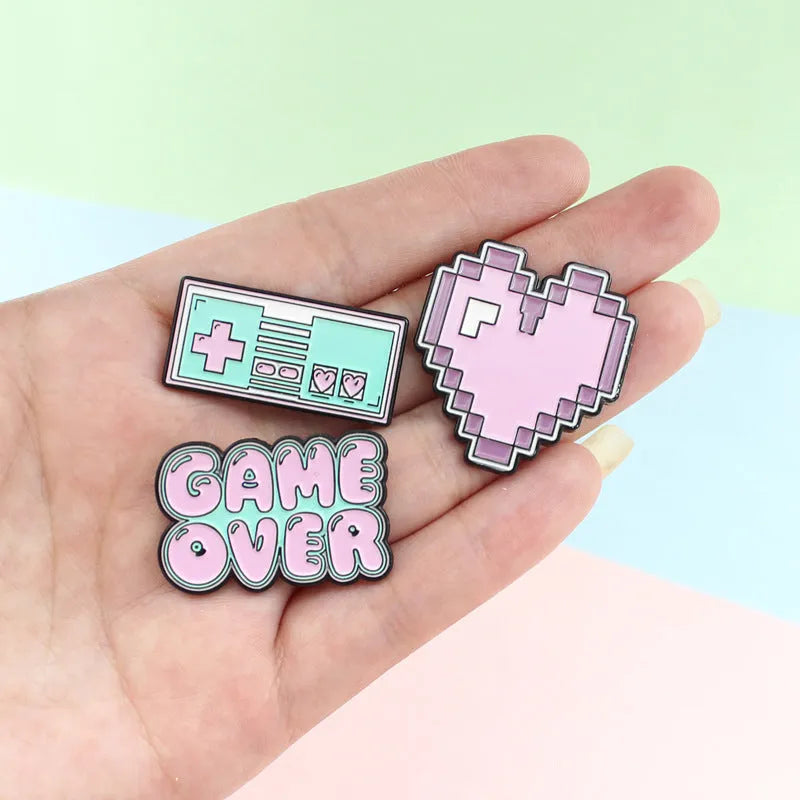 A three-dimensional die-cast alloy metal badge shaped like a stereo game console.