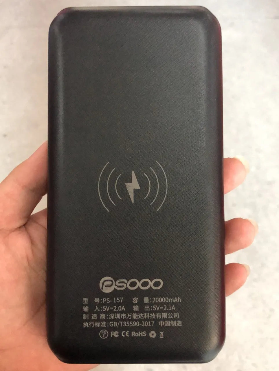 Black portable power bank with wireless Qi charging pad, three USB ports, and LED flashlight for iPhone Samsung Xiaomi phones
