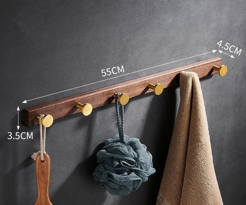 A row of black walnut bathroom clothes hooks with brushed brass metal details on a perforated mounting strip.