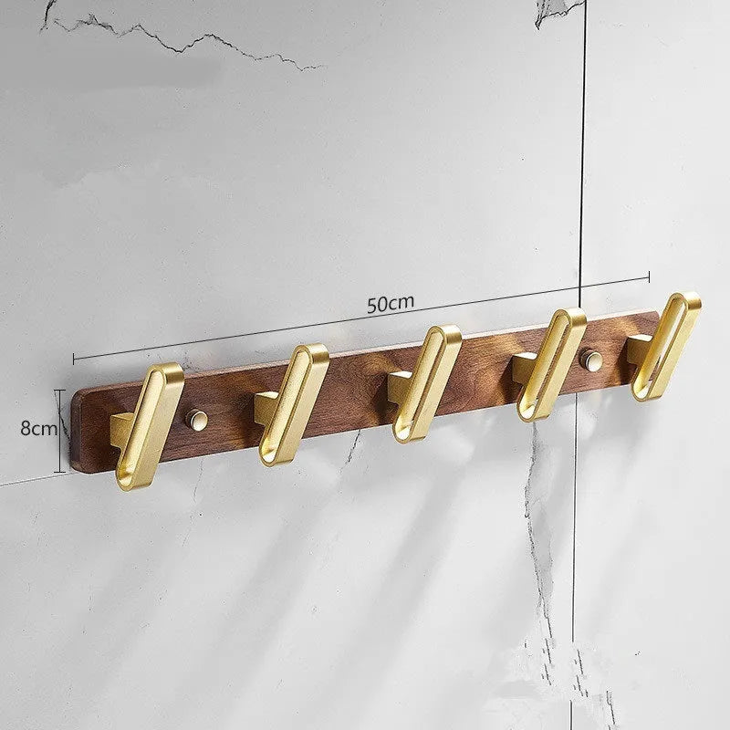 A row of black walnut bathroom clothes hooks with brushed brass metal details on a perforated mounting strip.
