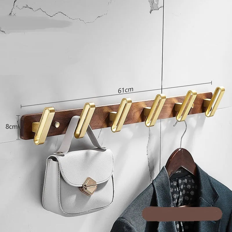 A row of black walnut bathroom clothes hooks with brushed brass metal details on a perforated mounting strip.