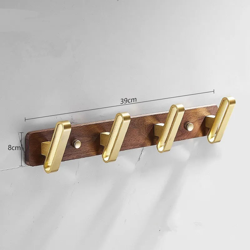 A row of black walnut bathroom clothes hooks with brushed brass metal details on a perforated mounting strip.