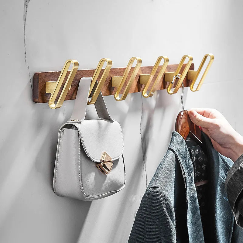 A row of black walnut bathroom clothes hooks with brushed brass metal details on a perforated mounting strip.