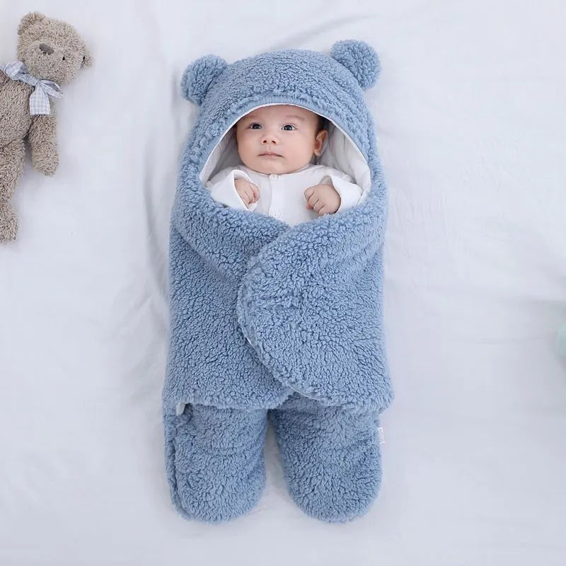 A baby quilted sleeping bag wrapper in a cotton blend fabric, shown in a light blue colour, laid flat.