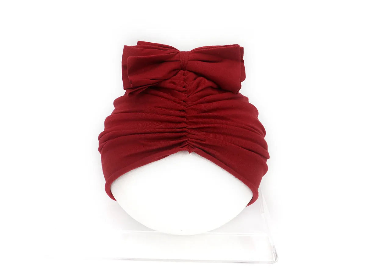 Soft acrylic knitted baby hat turban for infants and toddlers aged 0 to 28 months in a solid colour.