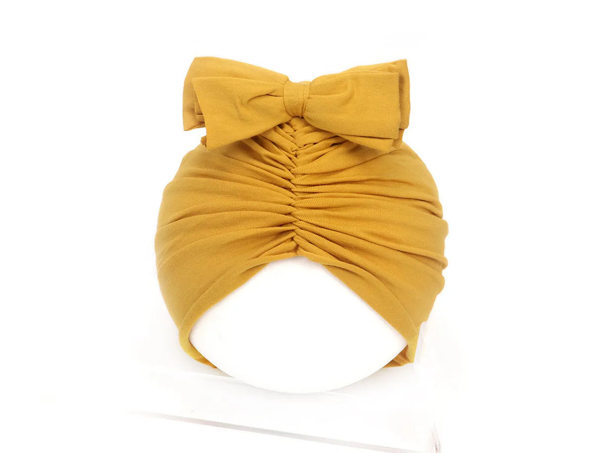 Soft acrylic knitted baby hat turban for infants and toddlers aged 0 to 28 months in a solid colour.