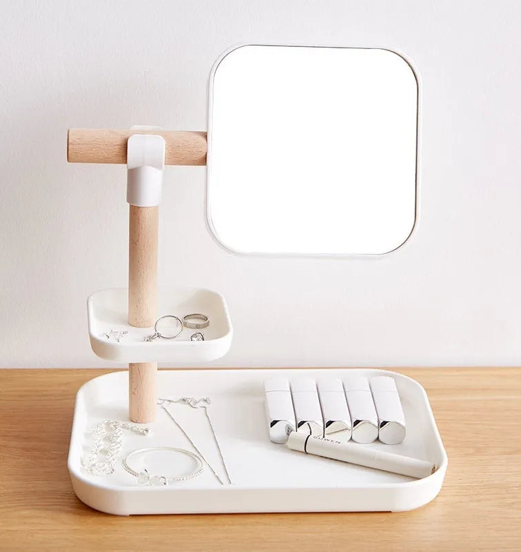 White desktop cosmetics storage box with mirror holding makeup brushes and lipsticks on a dressing table
