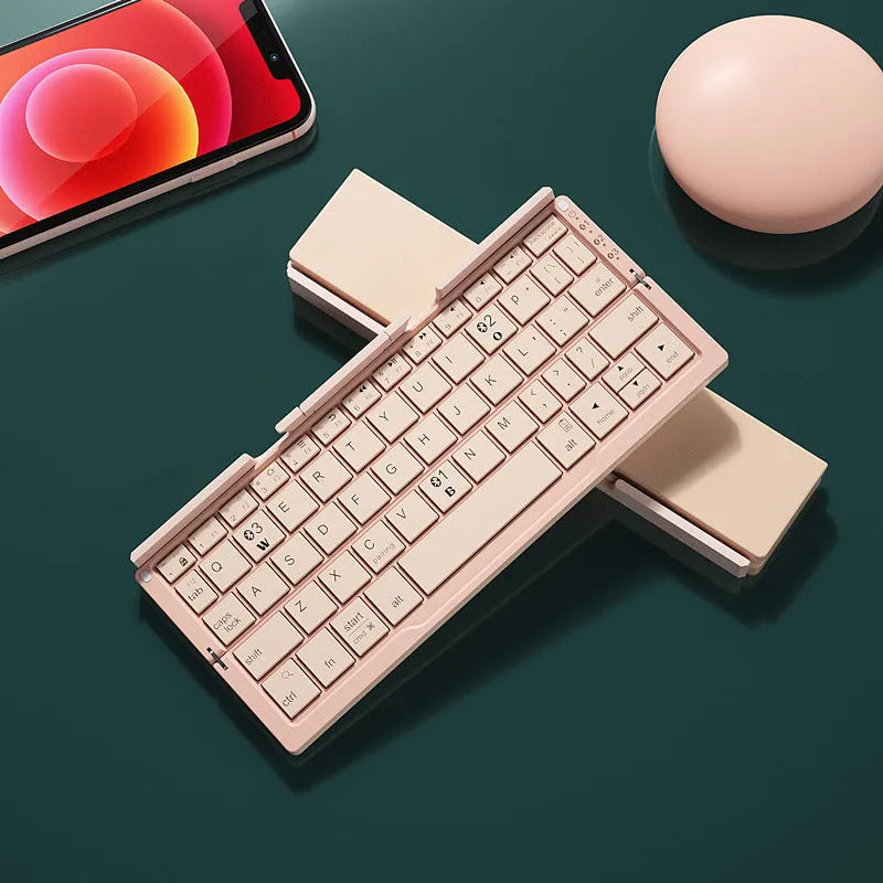Silver white folding Bluetooth keyboard with stand holding a smartphone, showing compact folded size