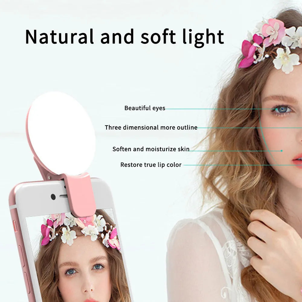 A white round clip-on LED mini fill light attached to a mobile phone.