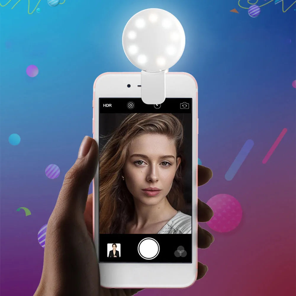 A white round clip-on LED mini fill light attached to a mobile phone.