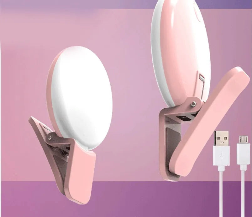 A white round clip-on LED mini fill light attached to a mobile phone.