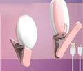 A white round clip-on LED mini fill light attached to a mobile phone.