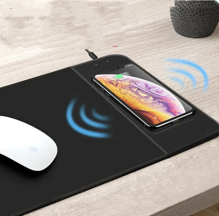 Black wireless charging mouse pad with RGB lighting edge on a wooden desk