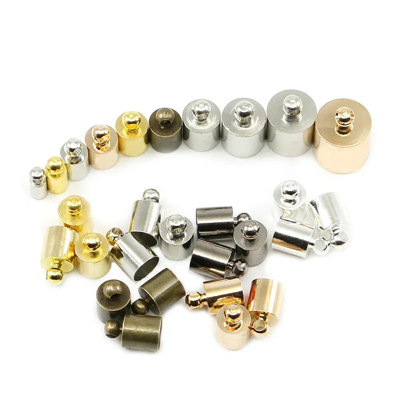 Assortment of small copper jewellery caps in different colours and sizes on a white background.