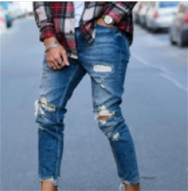 Deep blue men's jeans with distressed hole details and five pockets laid flat.
