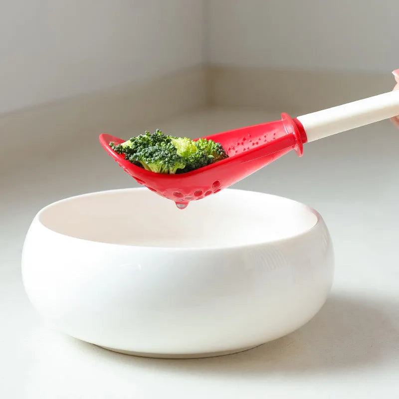 Red and black multifunctional plastic cooking spoon with serrated edges and slotted head on a grey background