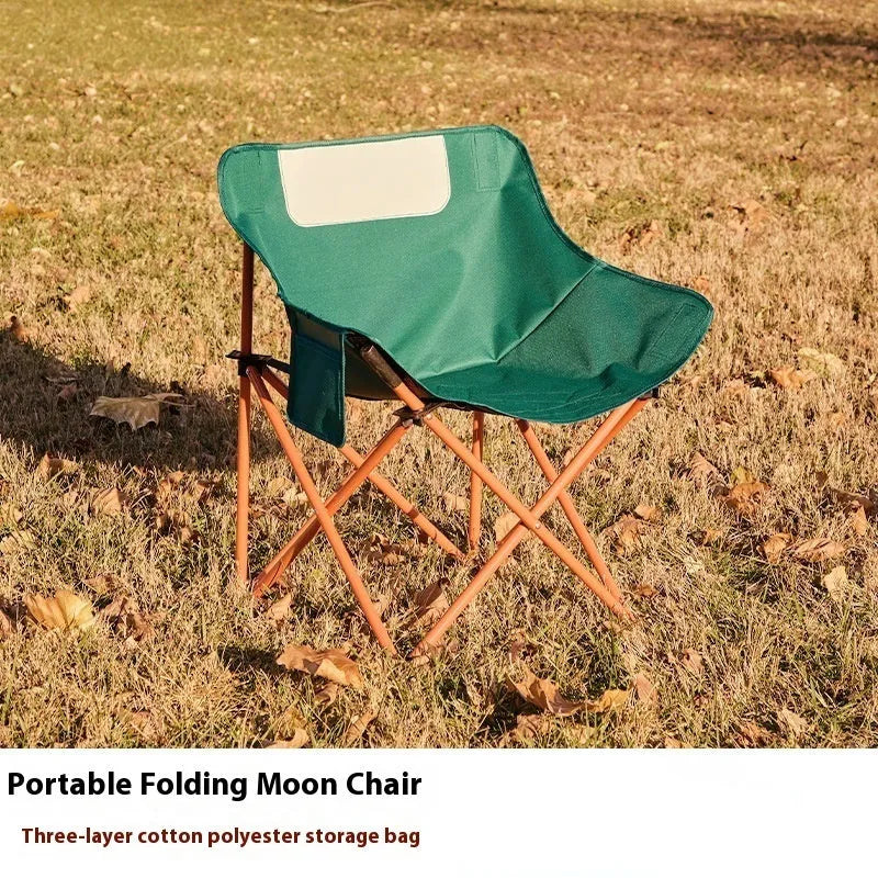 Beige portable folding camping chair with steel frame on grass outdoors